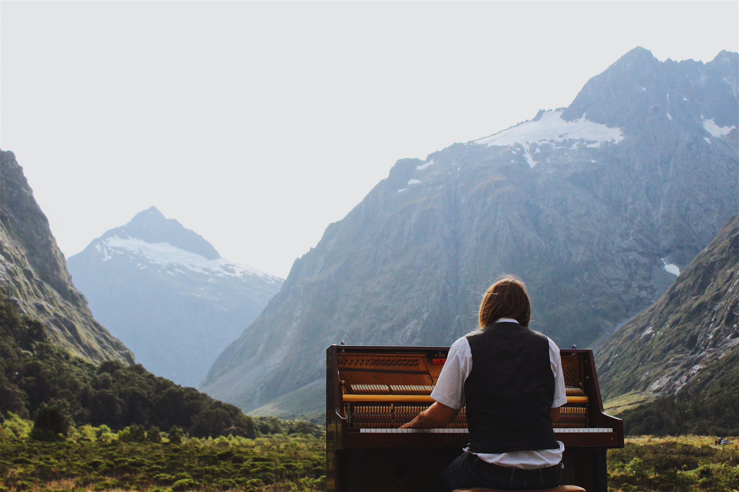 person sitting by New Zealand mountains