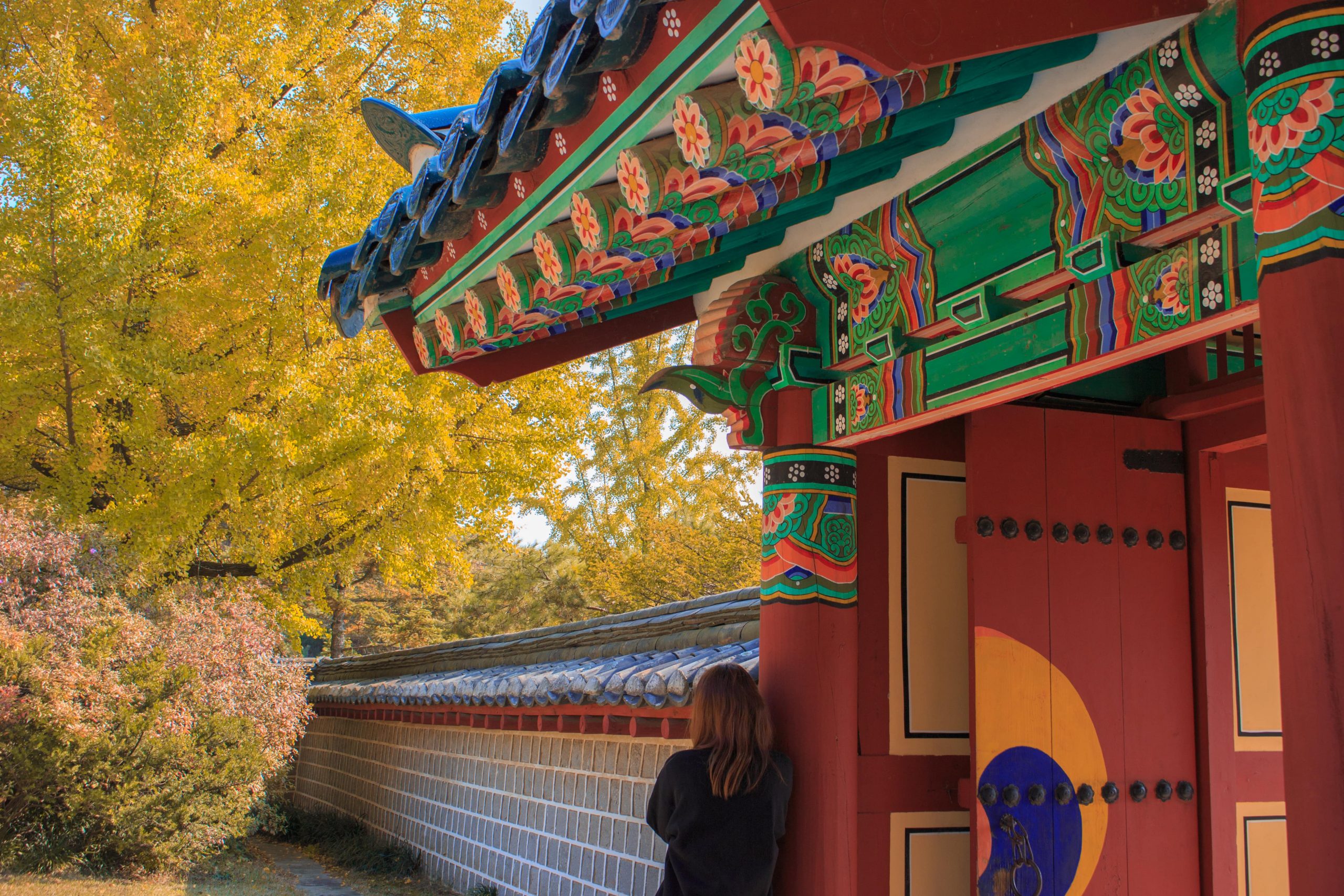 A woman leaning against a traditional Korean building.