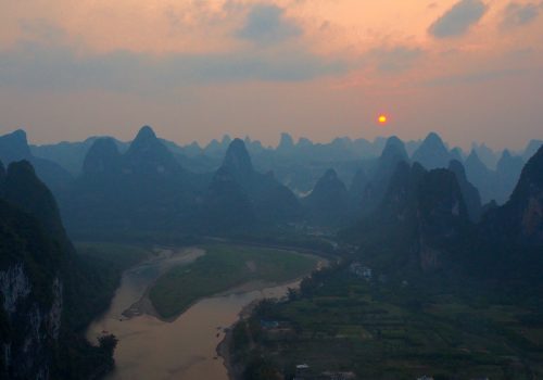 A mountain range with the sun setting in the background.