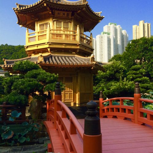 A bright red bridge leading to a gold-painted tower in traditional Chinese design.