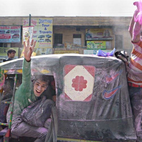 A group of smiling Indian men throwing glitter into the air.
