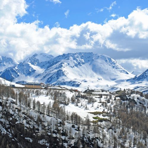 Snow-covered mountains and forests, with a large hotel looking small next to the mountains.