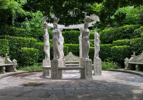 Four statues in a circle with stone benches around them.
