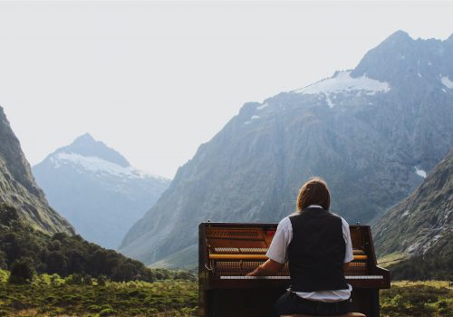 A student playing piano in front of mountains in New Zealand