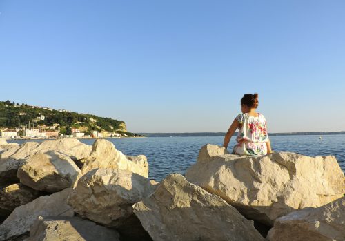 A student sitting on a rock looking out at the ocian