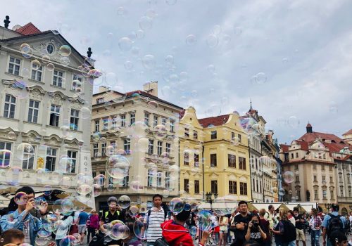 A crowd of people celebrating and blowing bubbles in Prague.