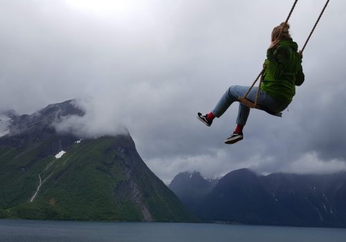 A student swinging on a rope swing over a Fjord in Norway.
